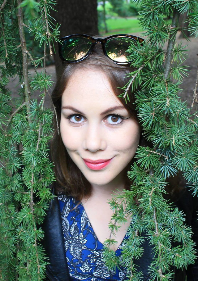 Woman standing in between the branches of a tree. 